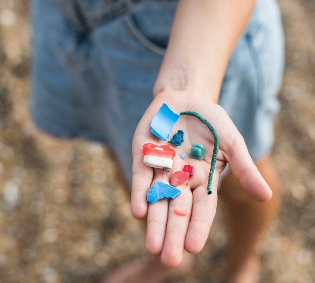 Child's hand holding pieces of plastic pollution